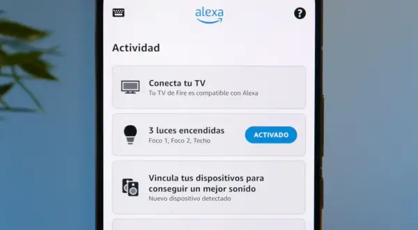 Pantalla de móvil con la app Alexa. Muestra "Actividad", "Conecta tu TV", "3 luces encendidas" (activado) y "This Is Morat". Parece que Alexa no funciona bien.