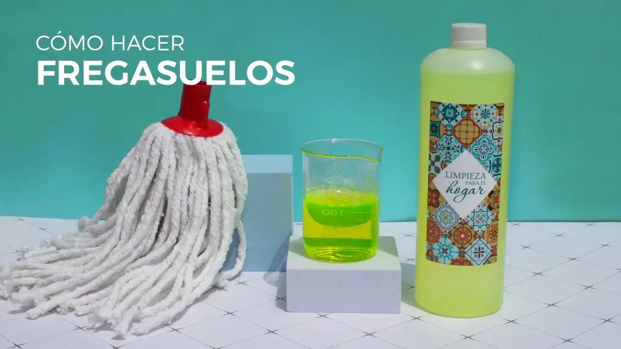 Un mocho blanco, un vaso con líquido verde brillante y una botella de limpiador para el hogar, listos para hacer un fregasuelos casero.
