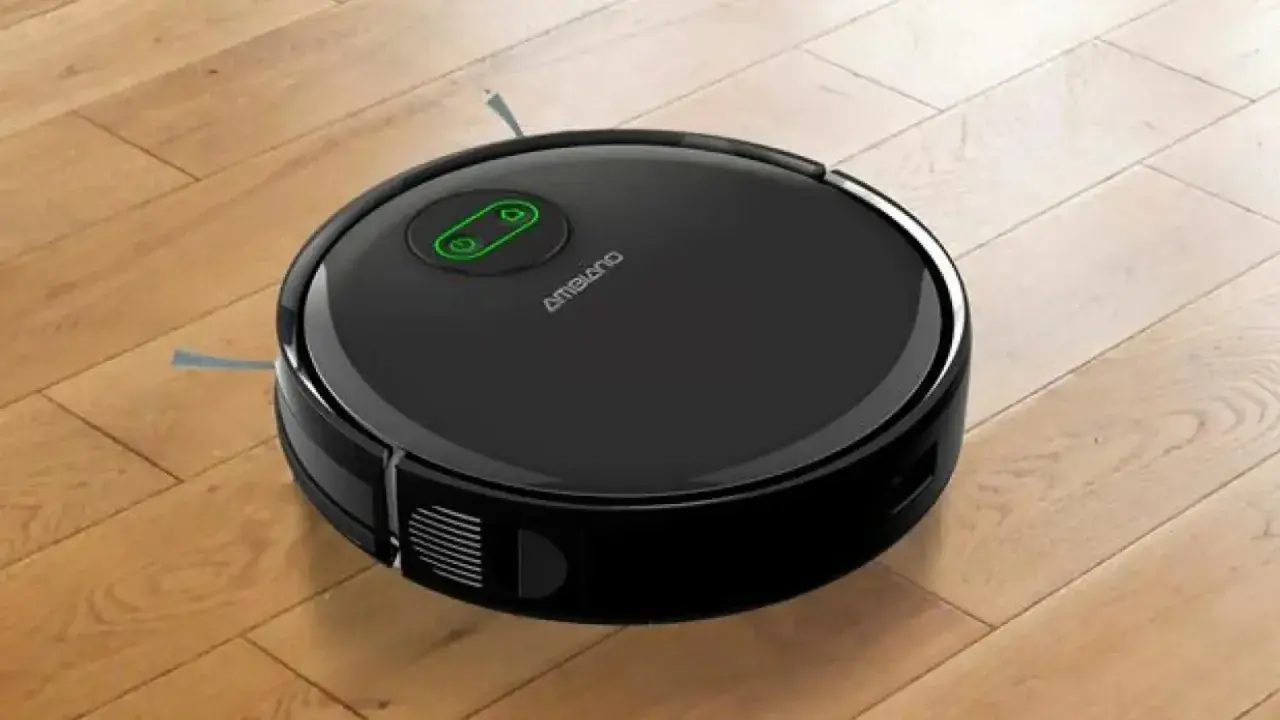 Robot aspirador negro sobre suelo de madera, listo para su reparación.