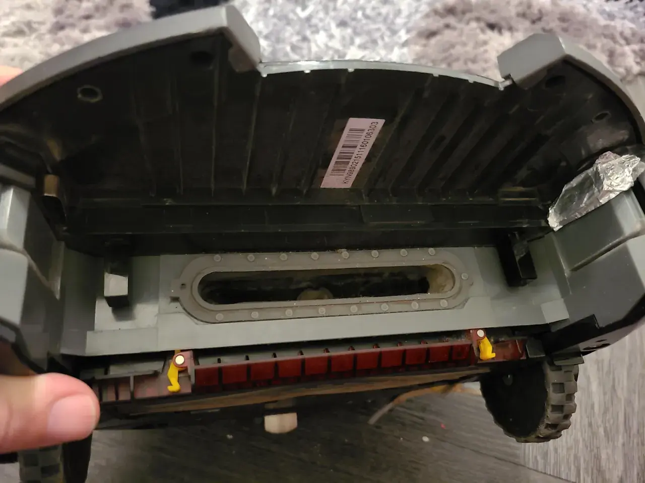 El robot aspirador Roomba muestra un error 10. Se ve el interior, con suciedad acumulada en el canal de succión y la escobilla.