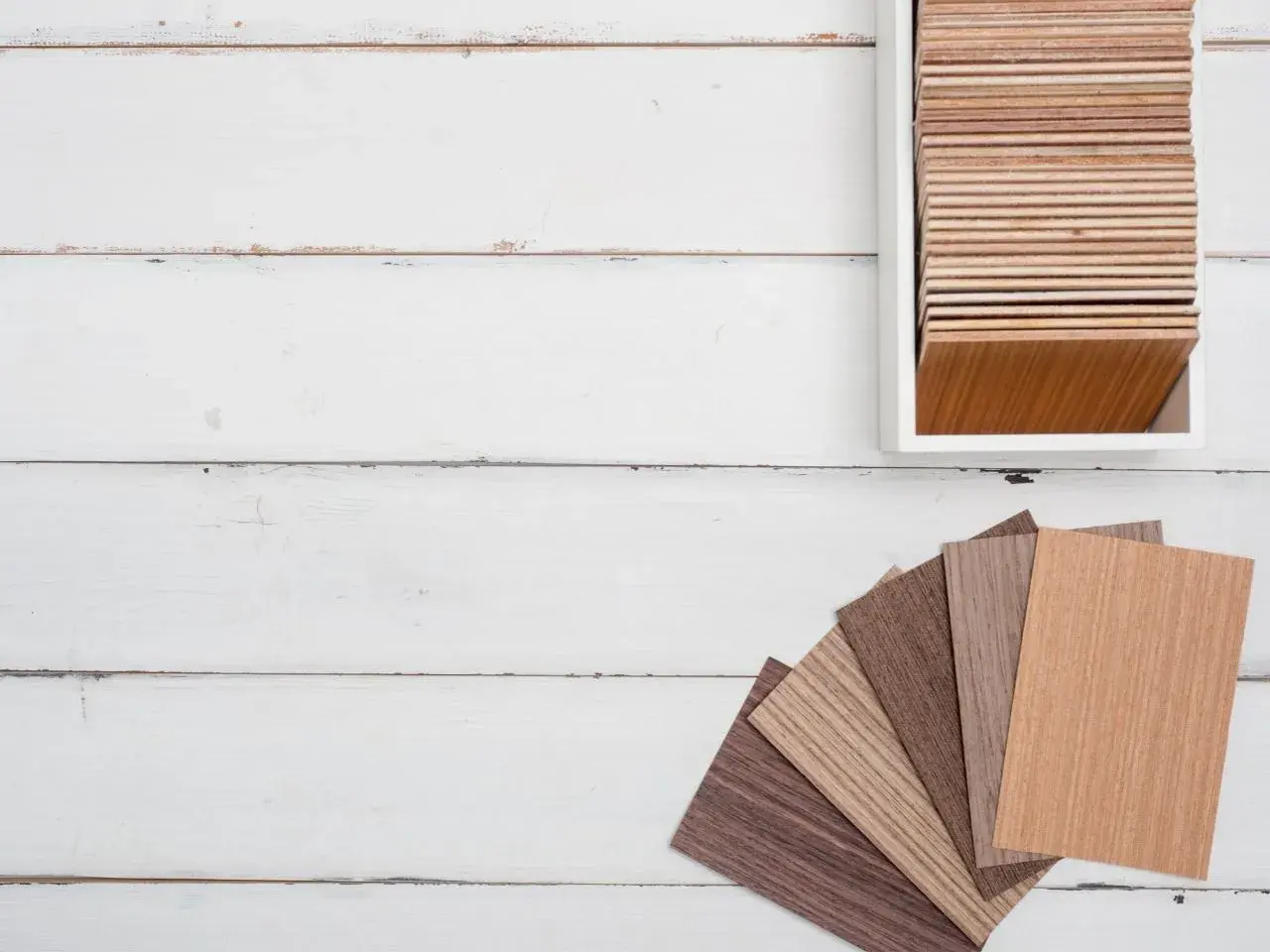 Muestras de parquet laminado de distintos tonos y grosores, dispuestas en abanico y en un expositor.