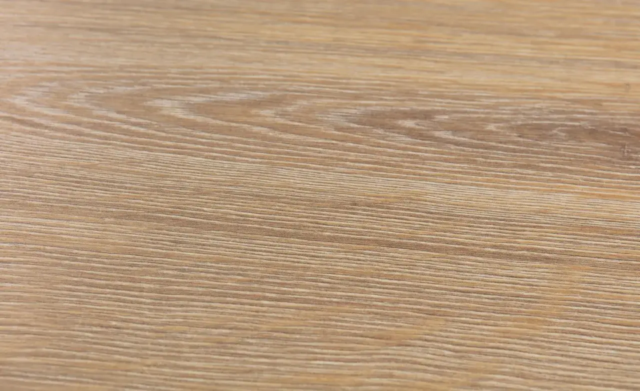 Textura de suelo laminado de madera clara, con vetas finas y paralelas. Podría ser un ejemplo de problemas de suelo laminado artens.