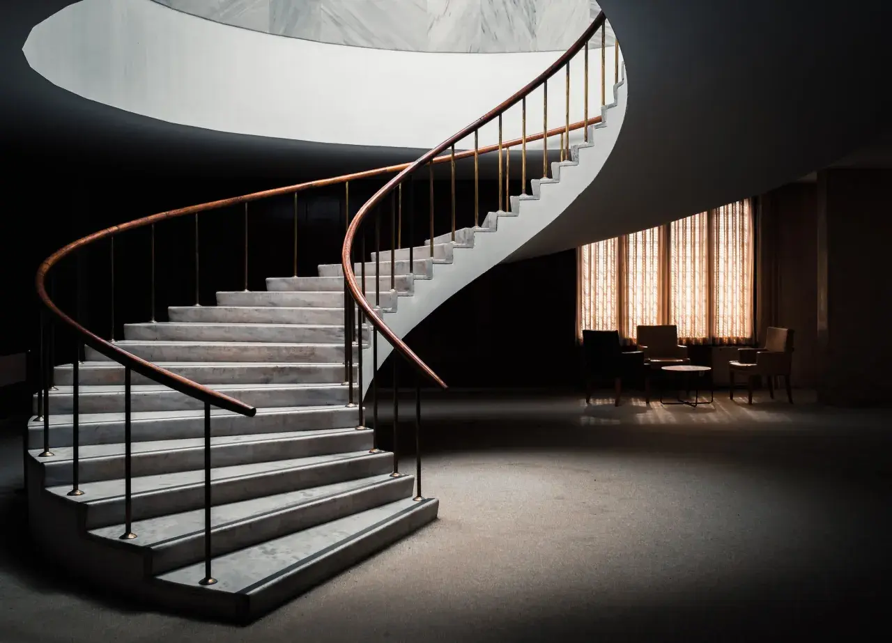 Escalera de caracol con peldaños de mármol y barandilla de madera. Diversos tipos de revestimientos para escaleras interiores.