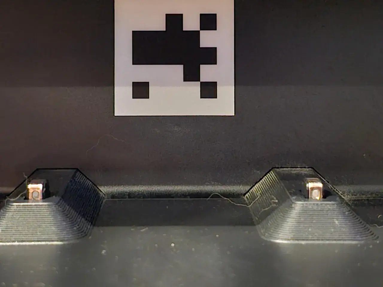 Dos contactos de carga de un Roomba, con un marcador QR encima. Posible error de carga 1.