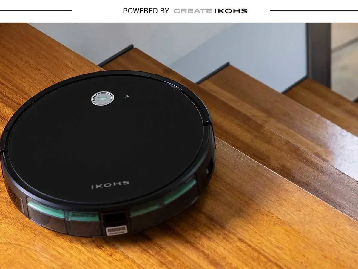 El robot aspirador Netbot S15, negro y redondo, se desliza por escalones de madera pulida, listo para limpiar.