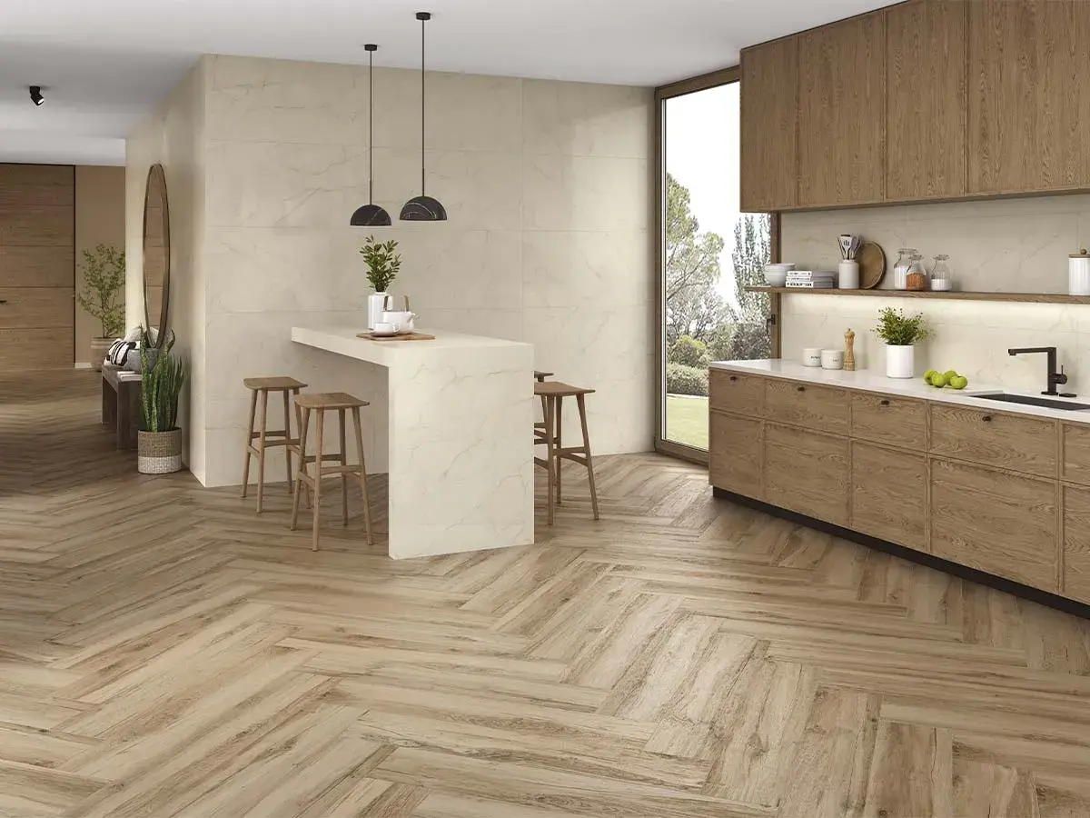 Cocina moderna con suelo de madera en espiga, el mejor suelo para cocina, isla con taburetes y muebles de madera.