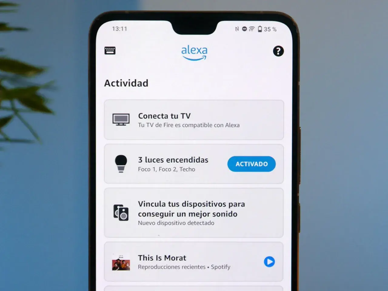 Pantalla de móvil con la app Alexa. Muestra "Actividad", "Conecta tu TV", "3 luces encendidas" (activado) y "This Is Morat". Parece que Alexa no funciona bien.