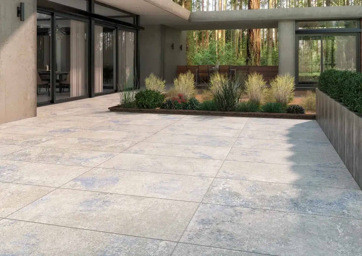 Terraza moderna con baldosas de piedra natural, el mejor suelo para exterior, rodeada de vegetación y con vistas a un bosque.