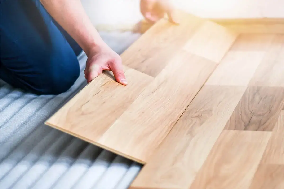 Man instalando un suelo de parquet flotante de madera clara.