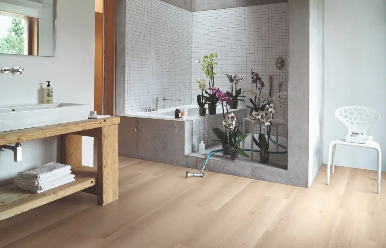 Tarima para cocinas y baños con un diseño moderno y natural. El suelo de madera clara complementa la bañera de hormigón y las orquídeas.