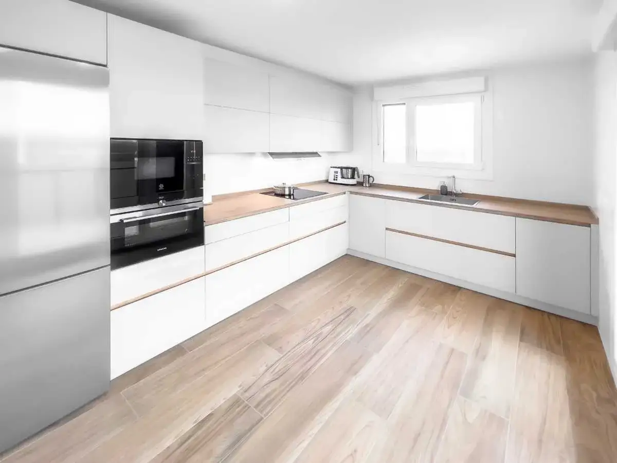 Cocina moderna con armarios blancos, encimeras de madera y un suelo de madera clara que parece el mejor suelo para cocina.
