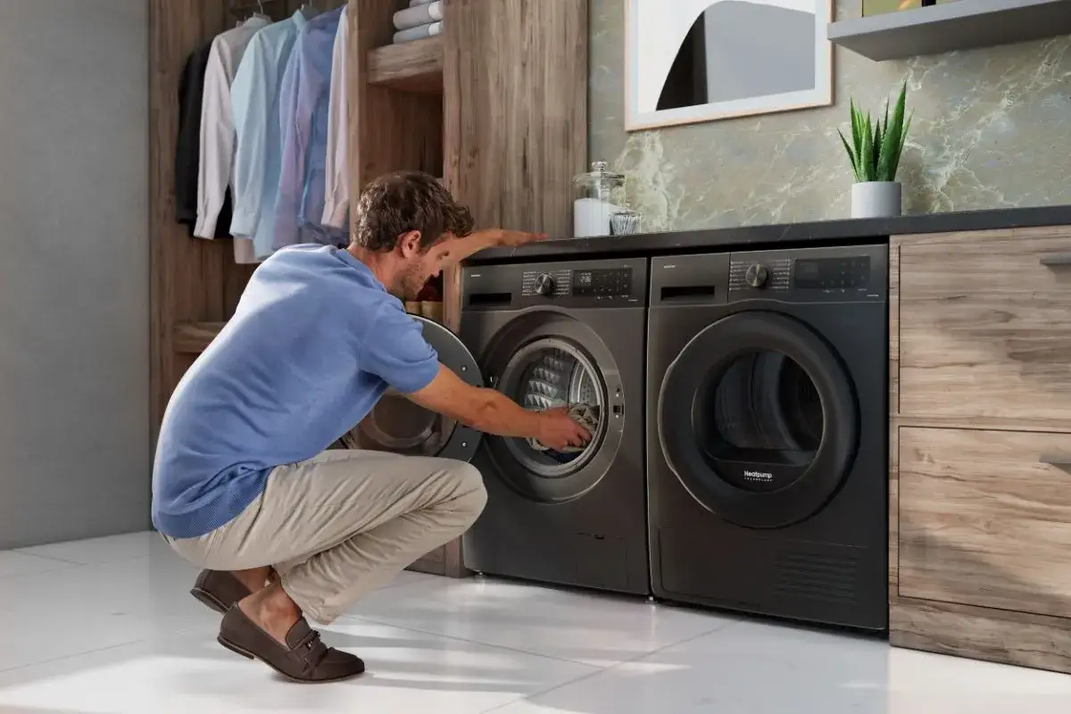 Hombre cargando ropa en una lavadora con vapor. &iexcl;Merece la pena lavadora con vapor para ropa impecable!