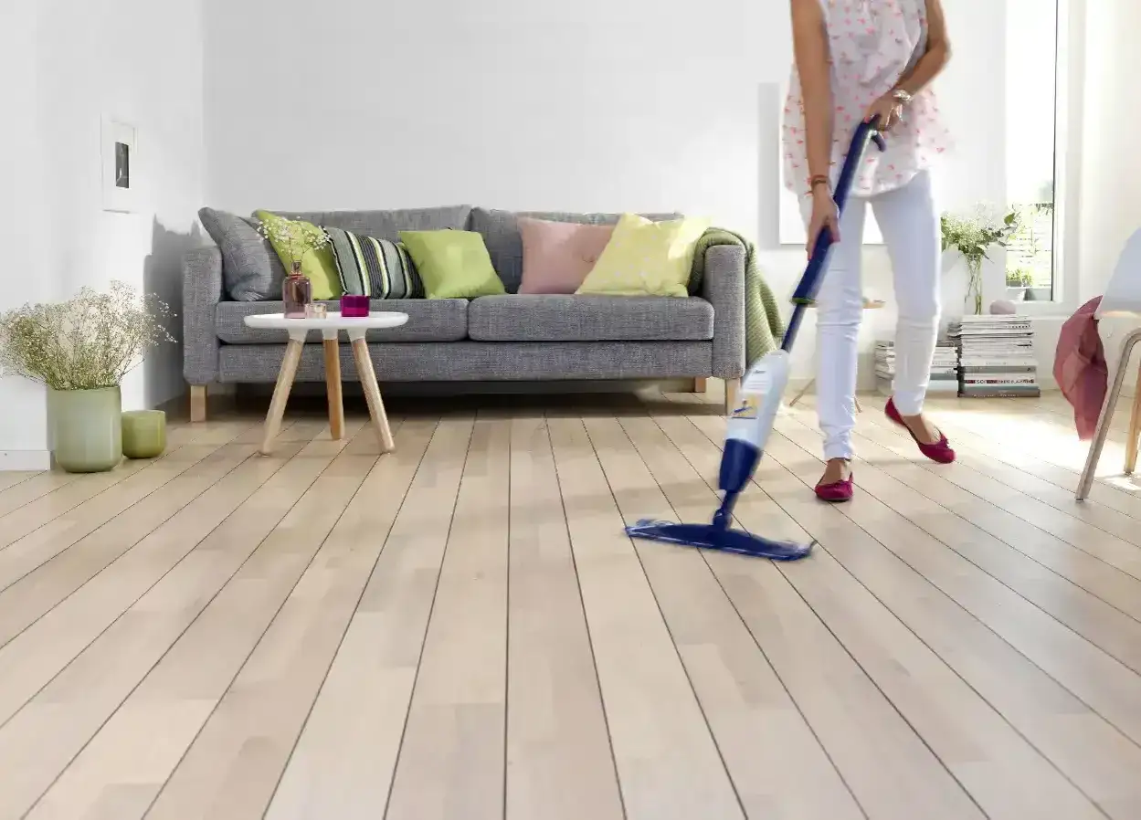 Persona limpiando suelo laminado despu&eacute;s de obra con mopa pulverizadora.