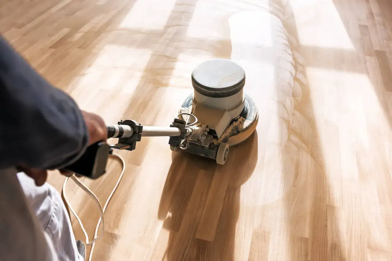 Un profesional realiza el mantenimiento de parquet con una pulidora, dejando el suelo de madera impecable y brillante.