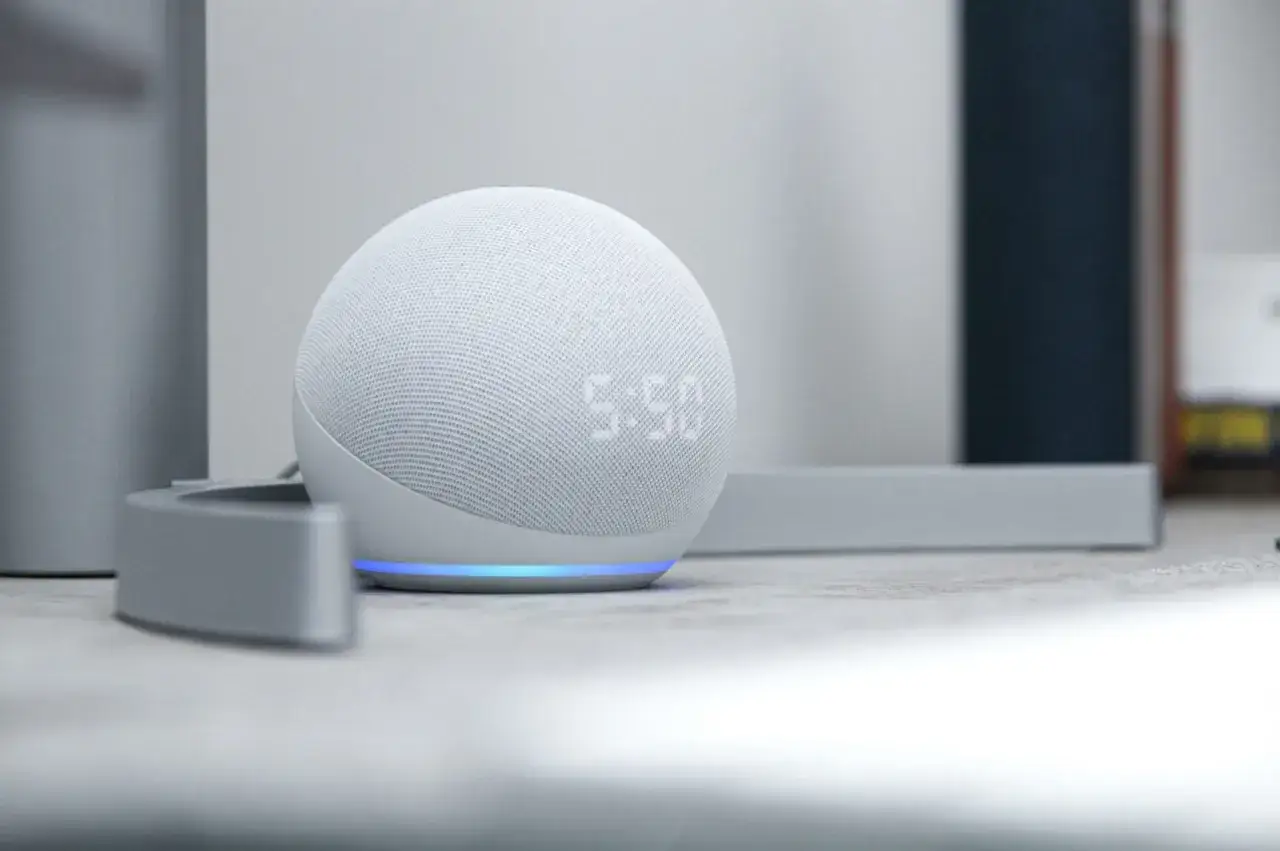 Altavoz blanco con pantalla LED mostrando la hora. La luz azul indica que est&aacute; listo para encender Alexa.