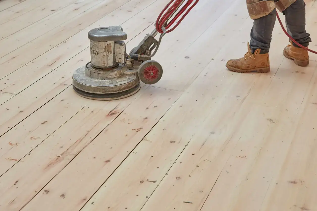 Un trabajador pule un suelo de madera con una m&aacute;quina. El parquet se puede acuchillar varias veces para renovarlo.