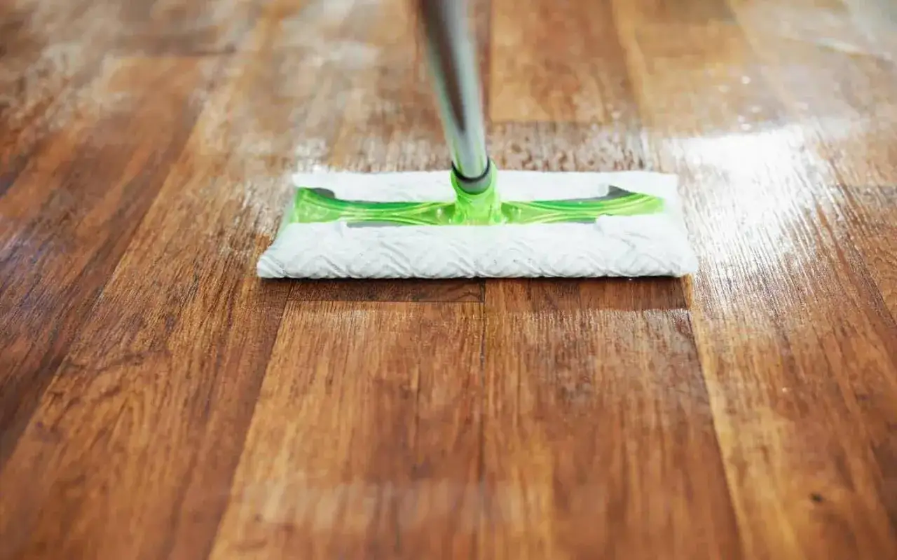 Mopa limpiando un suelo de vinilo con aspecto de madera, mostrando c&oacute;mo quitar rayas y dejarlo reluciente.