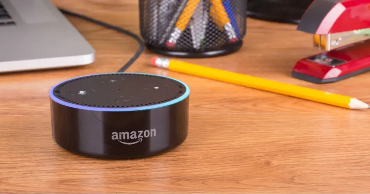 Alexa con luz azul indica problemas para conectarse a internet. En la mesa hay un port&aacute;til, l&aacute;pices y una grapadora.