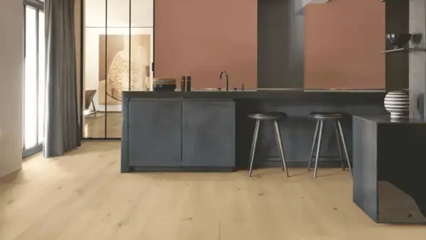 Cocina moderna con suelo vinílico adhesivo o click de madera clara, isla oscura y taburetes.