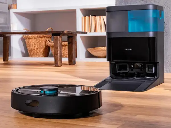 Robot aspirador negro junto a su base de carga con depósito azul.