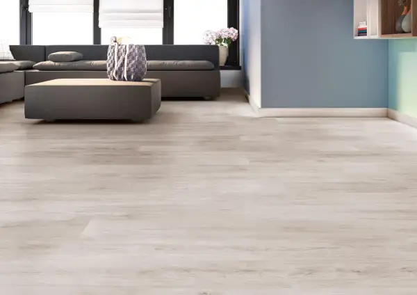 Suelos laminados colores actuales, con un sofá gris y una mesa de centro, en una sala de estar moderna.