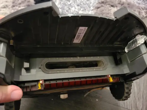El robot aspirador Roomba muestra un error 10. Se ve el interior, con suciedad acumulada en el canal de succión y la escobilla.