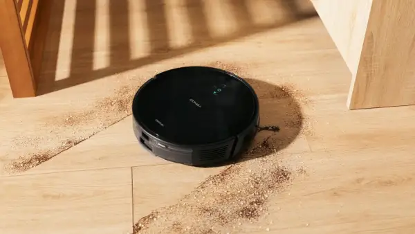 Robot aspirador Conga 999 en acción, limpiando la suciedad del suelo de madera.