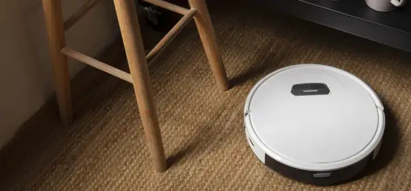 Robot aspirador Cecotec en alfombra de yute, cerca de las patas de una silla de madera. ¿Posibles averías?