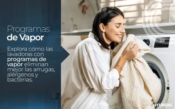 Mujer sonríe al oler ropa recién lavada. Una lavadora con programas de vapor merece la pena por su frescura y limpieza.