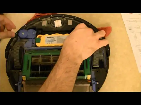 Mano arreglando un Roomba con **error 15**. Se ve la batería amarilla y las escobillas.