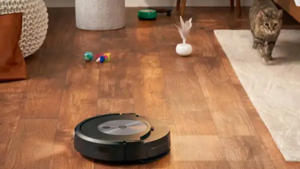 Un Roomba con error 17 se detiene en un suelo de madera. Un gato observa desde una alfombra.