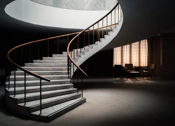 Escalera de caracol con peldaños de mármol y barandilla de madera. Diversos tipos de revestimientos para escaleras interiores.