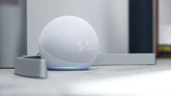 Altavoz inteligente Echo Dot con pantalla mostrando la hora. La luz azul indica que está listo para recibir ayuda de la app Alexa.
